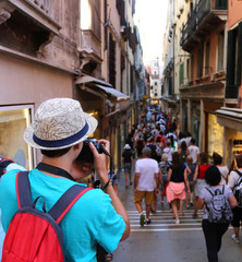 Young photographer takes a picture to people walking in the crow