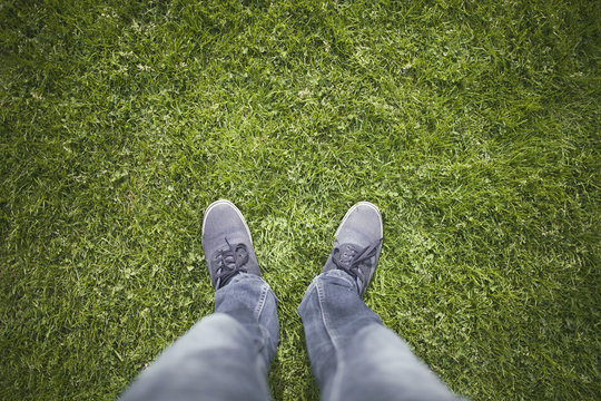 Top view man legs with shoes on green sunny grass.