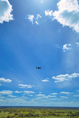 Flight of a gray quadrocopter against a blue sky.
