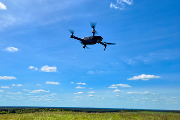 Flight of a gray quadrocopter against a blue sky.