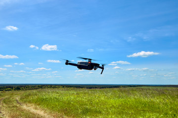 Flight of a gray quadrocopter against a blue sky.