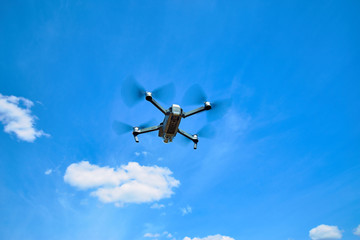 Fototapeta na wymiar Flight of a gray quadrocopter against a blue sky.
