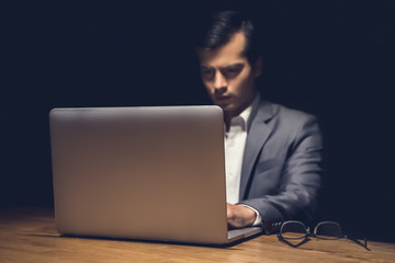 Businessman using laptop computer working late at night in dark room