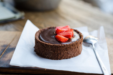 Chocolate tart with salted caramel, decorated with pieces of fresh strawberries.