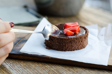 Chocolate tart with salted caramel, decorated with pieces of fresh strawberries.