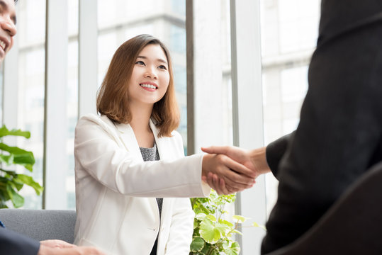 Asian business woman making handshake with client in office lounge