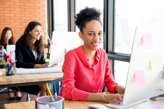 Smiling beautiful black businesswoman at working desk in creative office