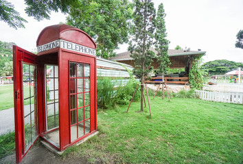 red vintage telephone booth in the green public park