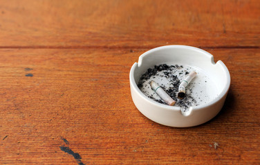 closeup white ashtray on wooden with over light in the background