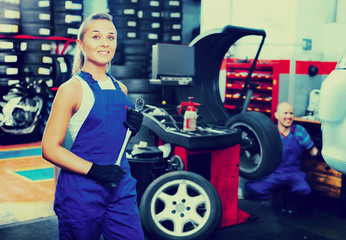 Mechanic woman working on new tire fitting in service point