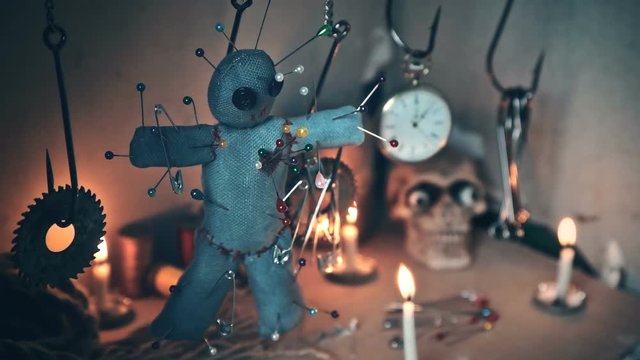 the voodoo doll swinging on the hook over the ritual table