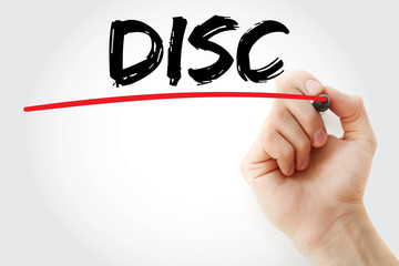Hand writing DISC (Dominance, Influence, Steadiness, Conscientiousness acronym - personal assessment tool to improve work productivity) with marker, concept background