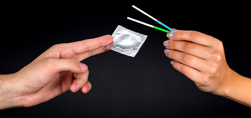 pregnancy test and a condom on black background
