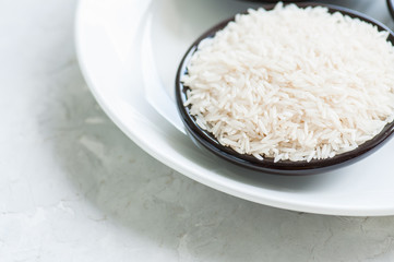 White jasmine rice in a plate on white stone background. Toned.
