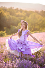 Beautiful girl in a field of lavender on sunset. Girl in amazing dress walk on the lavender field.