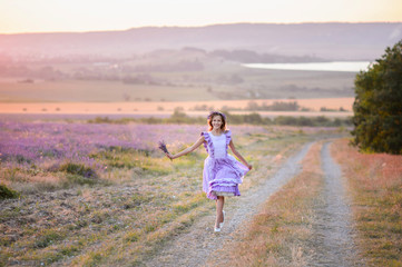 Beautiful girl in a field of lavender on sunset. Girl in amazing dress walk on the lavender field.