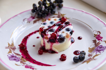 Cool jelly dessert with fresh blackberries and jam on a light plate. side view