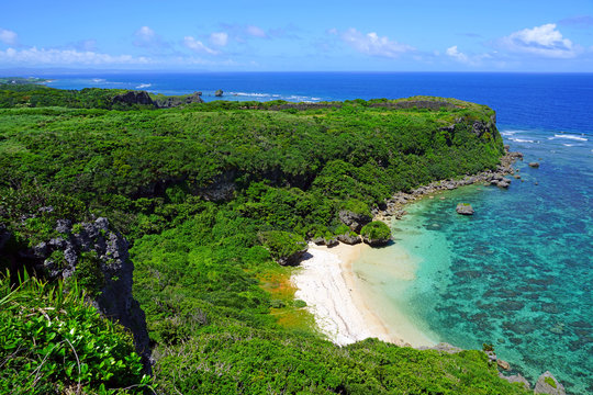 Landscape view of the Happy Cliff (Kafu Banta) overlooking the azure sea and a golden beach in Uruma, Okinawa, Japan