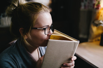beautiful young woman sniffing big book in room