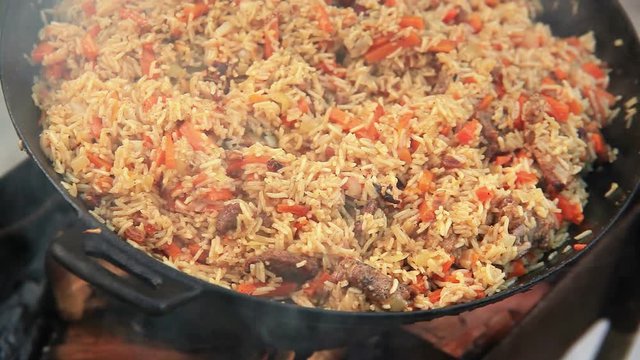 A huge bowl of pilaf (Middle East traditional food of rice and meat) cooks on the open fire