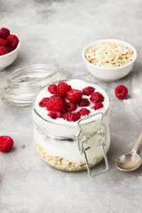 Glanola in glass jar with raspberry and mint on a gray background