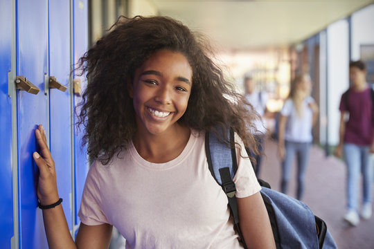 Portrait of black teenage girl by lockers in school corridor