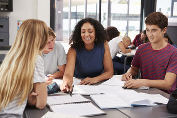 Teacher studying school books in class with high school kids