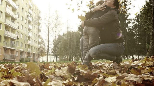 Unsaturated footage of son bringing a bundle of fallen autumnal leaves to his mum