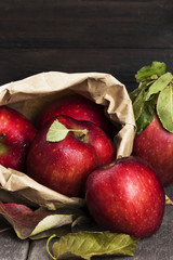 Apples in paper package on a dark wooden background