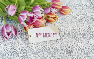  tulips flowers with happy birthday card on a lace background