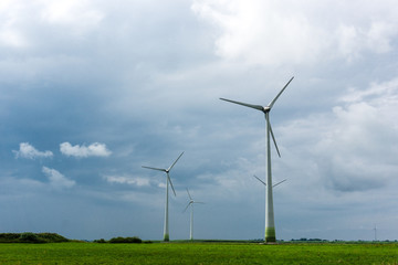 Fototapeta premium Wind Turbines and green fields on a cloudy day. Near storm