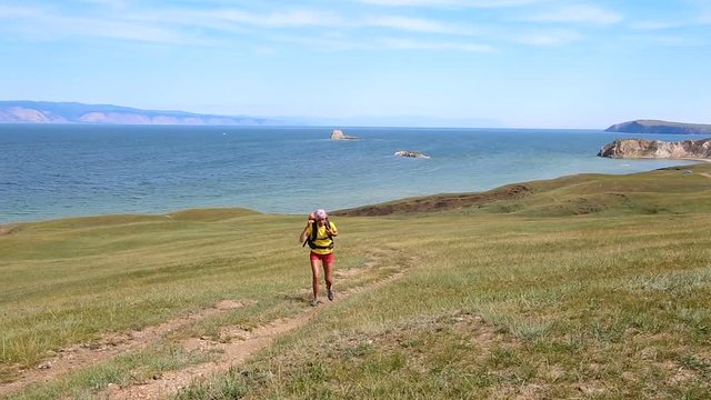 Woman hiker walking. Hiking girl walking alone in beautiful landscape nature. Caucasian girl living healthy lifestyle. Olkhon island, Lake Baikal, Russia