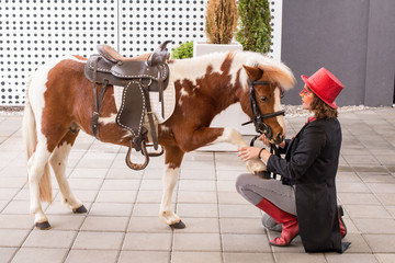 Lady with red shiny top hat and her pony