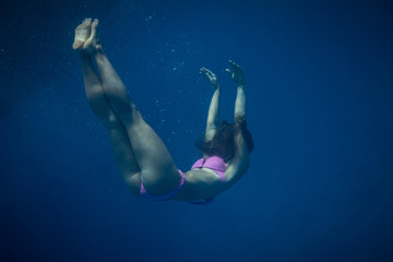 Fototapeta na wymiar A grirl drowning in the sea water. Underwater shot in marine background