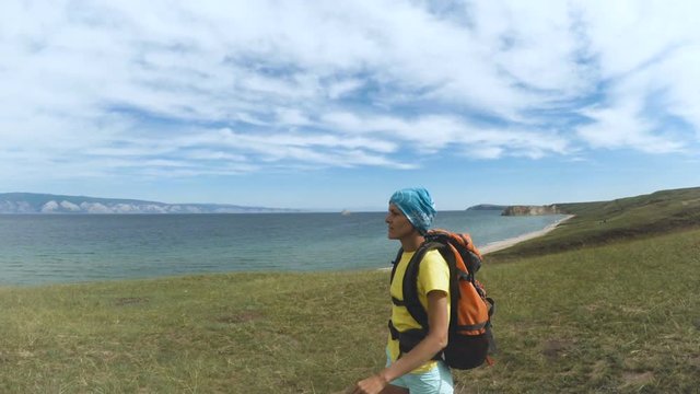Hiking woman trekking along blue lake Baikal. Female hiker walking on trek with backpack. Caucasian girl living active lifestyle. Olkhon Island, Baikal, Russia, Siberia
