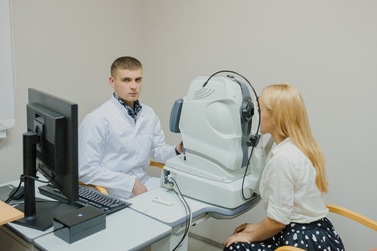 Young beautiful doctor/eye specialist/optometrist in an ophthalmologic clinic dooing a patient a Tomography