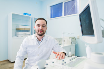 Naklejka na ściany i meble Male doctor with ultrasonic equipment during ultrasound medical examination