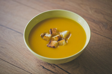 Pumpkin and carrot soup with crackers and parsley on wood background with Slices of bread