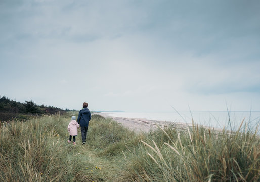 Rear view of brother and sister walking on grassy field