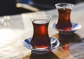 Black herbal turkish tea in traditional glass at the street cafe. Back light