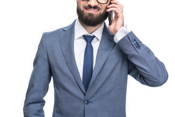 Naklejka premium cropped view of smiling businessman in grey suit using smartphone, isolated on white