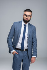 confident handsome businessman posing in grey suit, isolated on grey