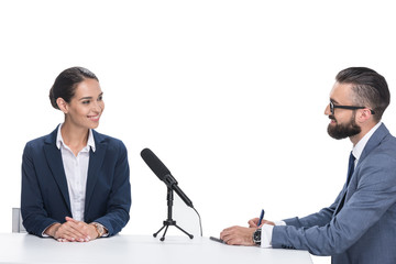 smiling male journalist interviewing businesswoman in suit, isolated on white