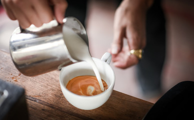 Coffee maker pouring the milk for make latte art