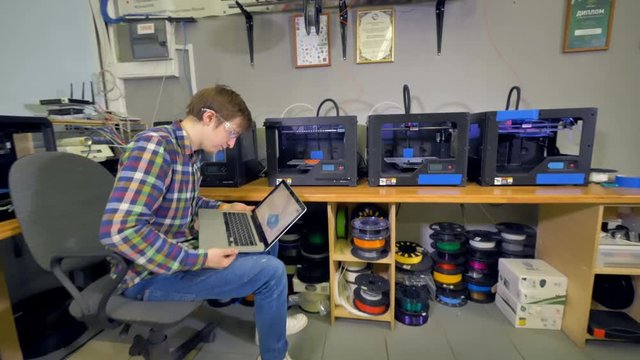 A man in charge of a 3d-printing process. 