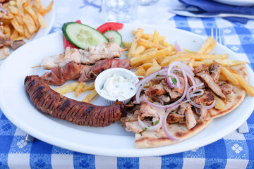 Traditional Greek Gyros plate with souvlaki, skewers, Tzatziki, bread and chips