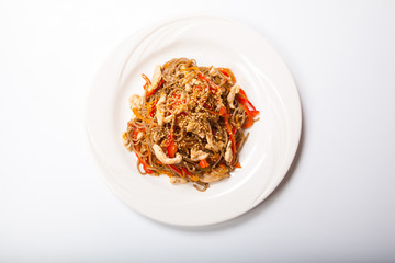 Italian pasta with chicken and peppers in a white plate on a light background