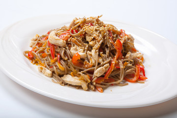 Italian pasta with chicken and peppers in a white plate on a light background