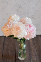 beautiful light beige and pink peonies on a dark wooden background