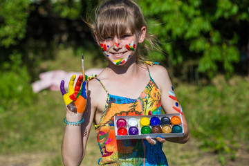 Cheerful cute girl playing with bright paints in the park. Have fun. Art and painting concept